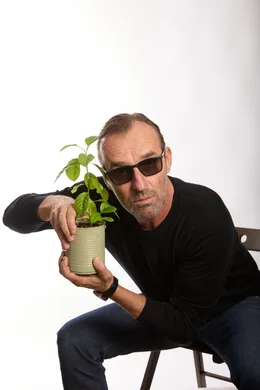 homme assis sur une chaise avec une plante dans les mains