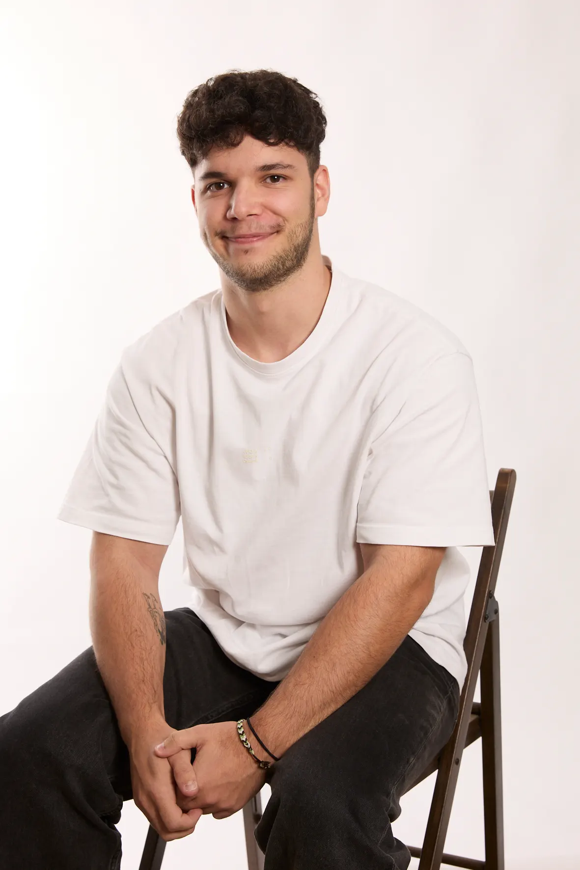 <p>jeune homme avec un t-shirt blanc assis sur une chaise</p>
