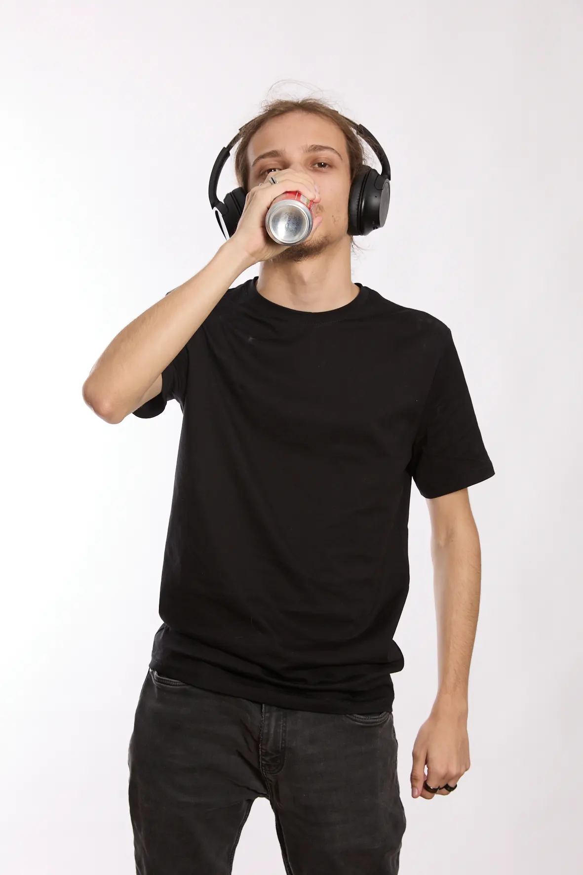 <p>jeune homme qui boit une canette de boisson sucrée en écoutant de la musique</p>
