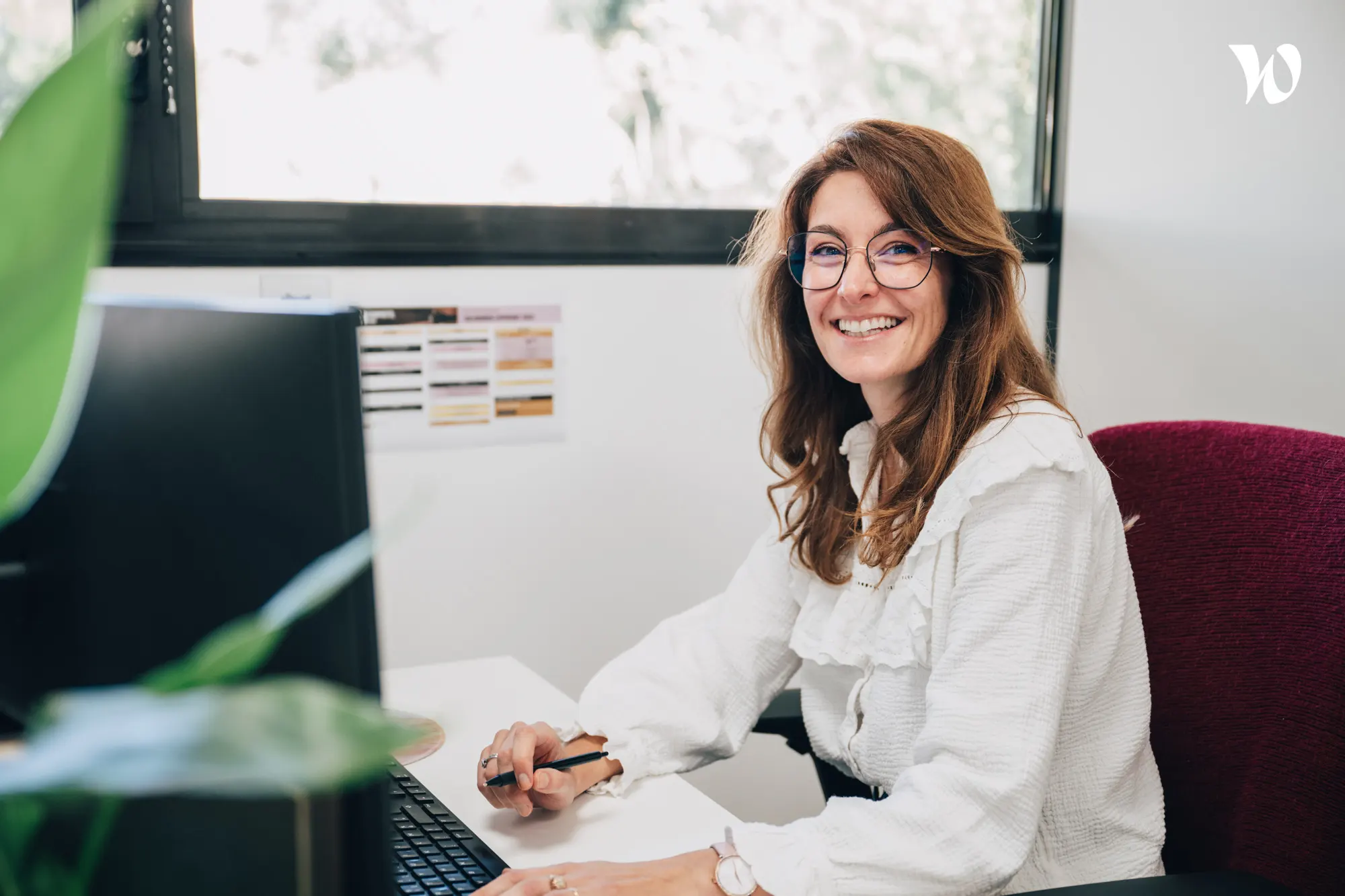 <p>femme très souriante assise à son bureau qui regarde la caméra</p>
