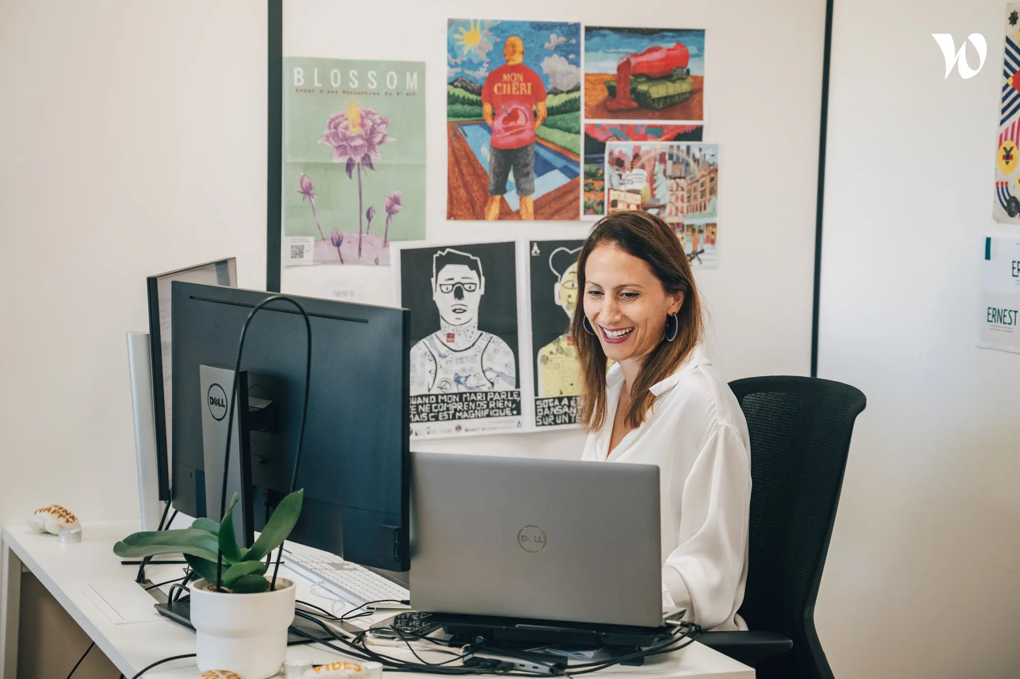 <p>femme souriante assise à son bureau </p>
